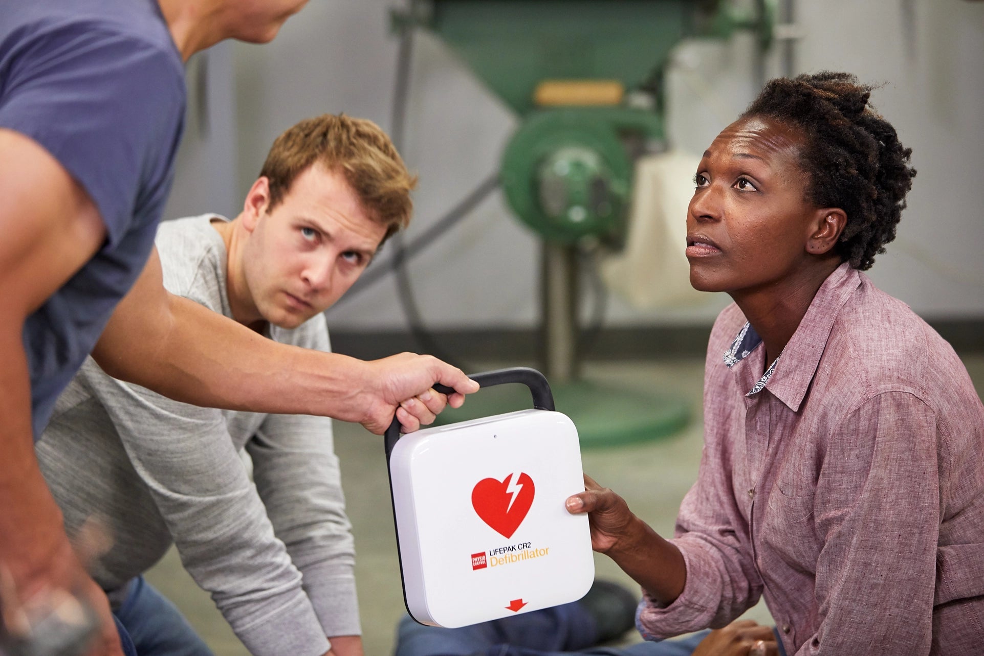People practicing CPR with an automated external defibrillator (AED) in a training session.