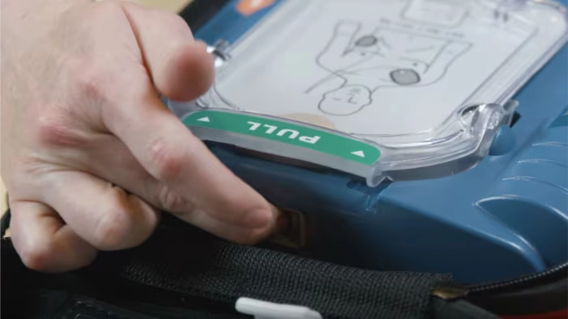 A hand pulling the lever on a blue automated external defibrillator (AED) case.