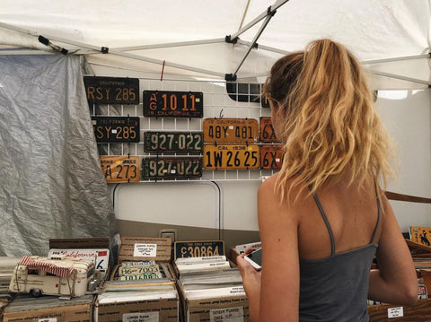 girl looking at antique licence plates at outdoor street fair 