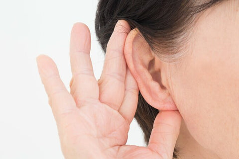 耳に手を当てる女性の耳のアップ写真