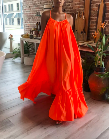  A woman flaunts a bright orange flowy maxi dress.