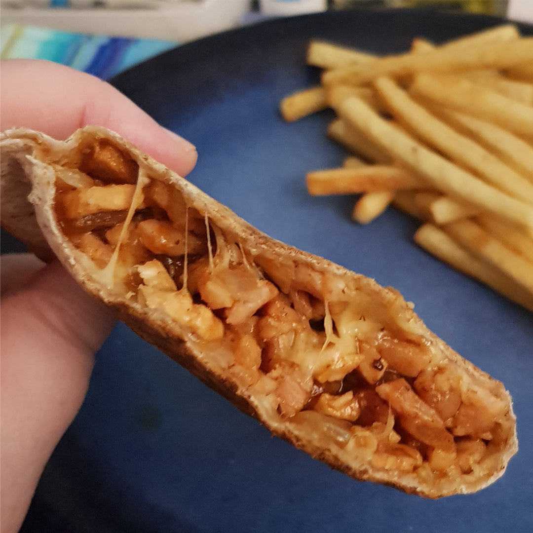 A toasted snack with chicken and cheese filling. French fries served on the side. 