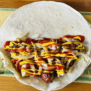 A tortilla filled with meat, mustard and ketchup