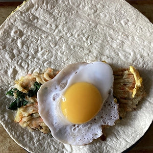 A tortilla filled with chicken and a fried egg