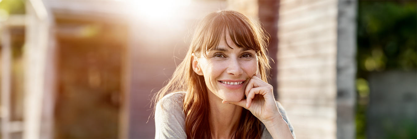 s-h-frau-laechelnd-sitzend-hinterhof-GettyImages-1175114047.jpg__PID:4582f0ba-53a0-426b-8f80-d3e16d4d9364