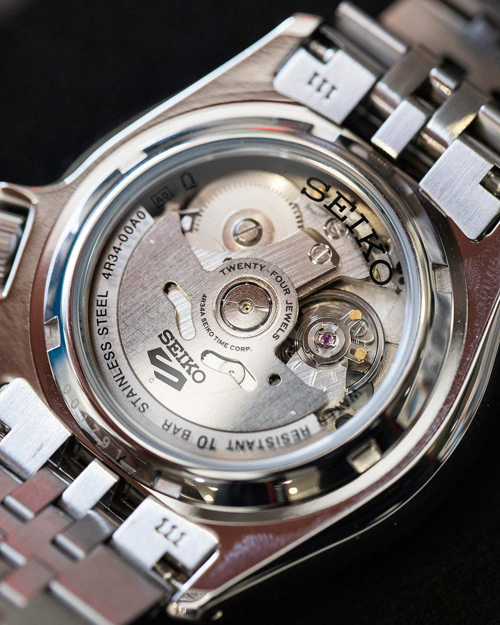 Seiko GMT See-through back. Automatic movement on display against black background. 