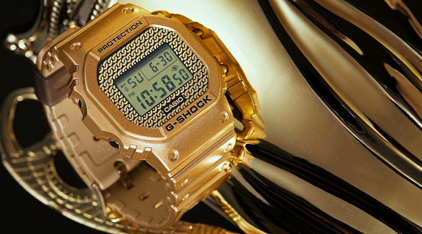 G-Shock Gold Chain DWE-5600HG-1. G-shock watch with background of gold jewellery.