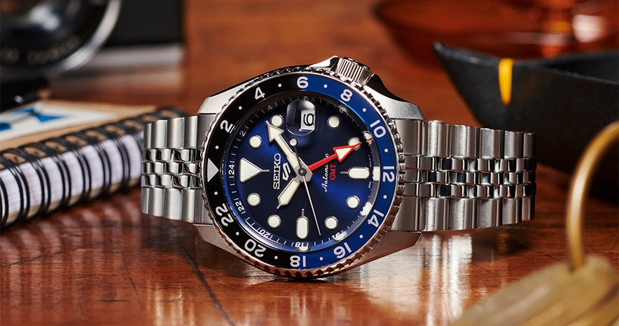 New Seiko GMT watches. Blue and black SSK003K set on a wooden table.