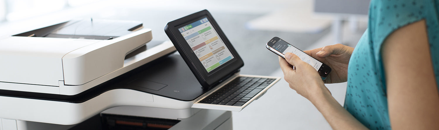 Person at printer holding phone and making copies