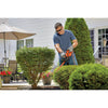 A man is using a BLACK+DECKER Electric Hedge Trimmer for trimming the shrubs.