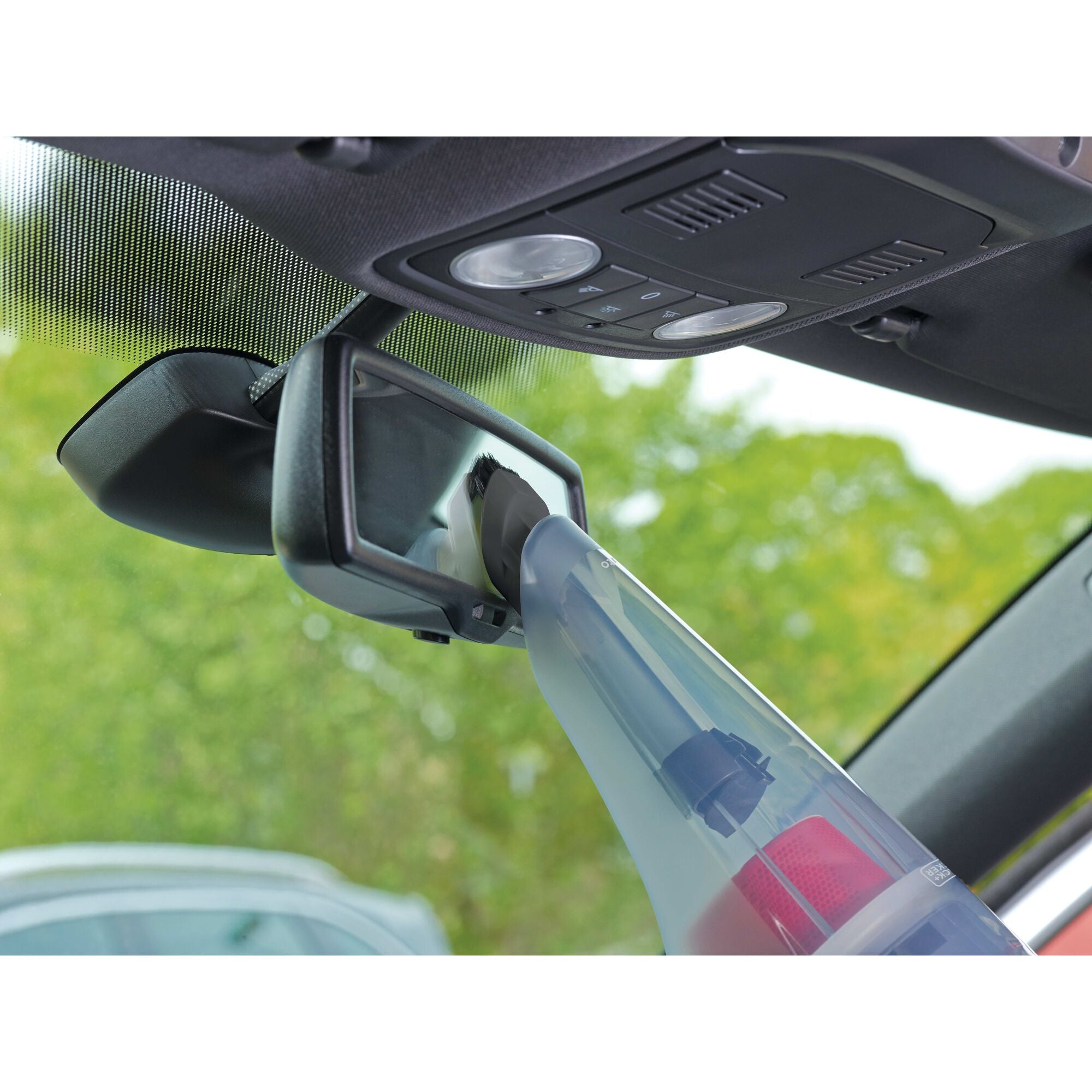 Compact Car Vacuum being used to clean a rear view mirror of a car.