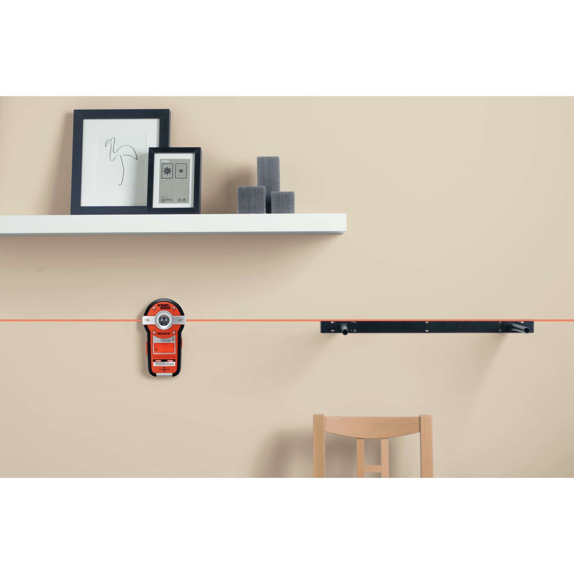 Bullseye auto leveling laser with stud sensor being used to measure a wall.