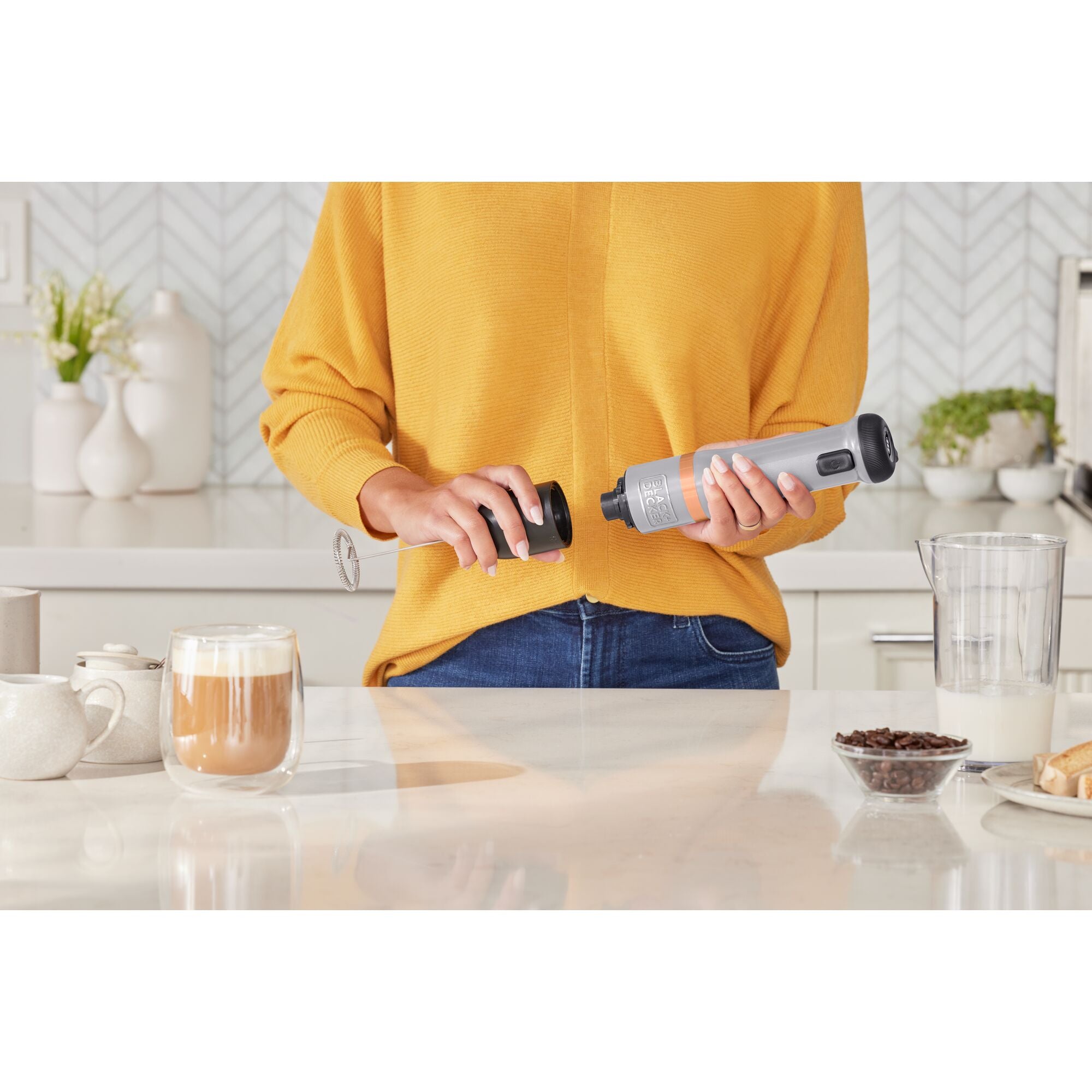 Talent adding frothed milk to a coffee drink featuring the BLACK+DECKER kitchen wand milk frother attachment