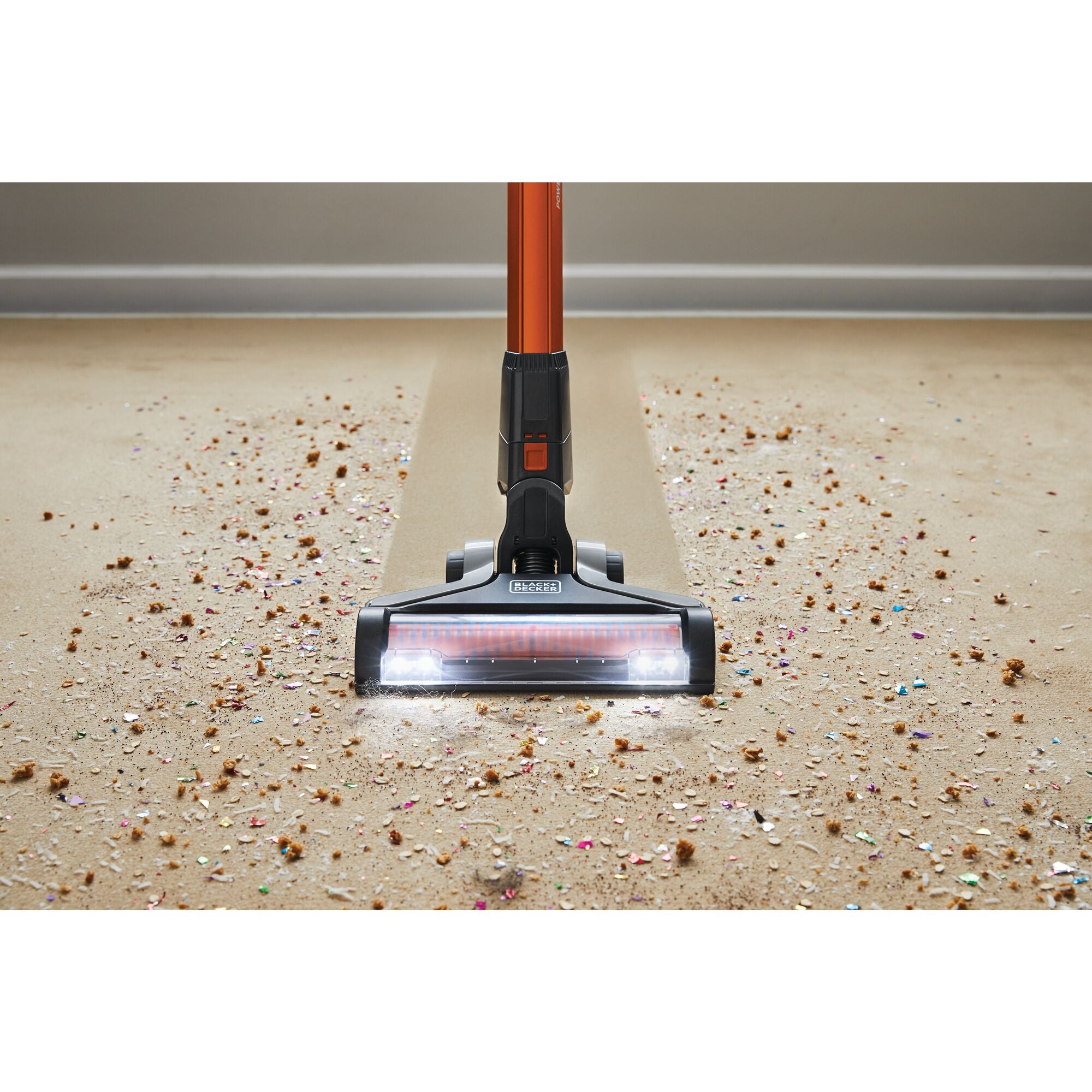 POWER SERIES Extreme Cordless Stick Vacuum Cleaner being used to clean debris from rug and wooden floor.
