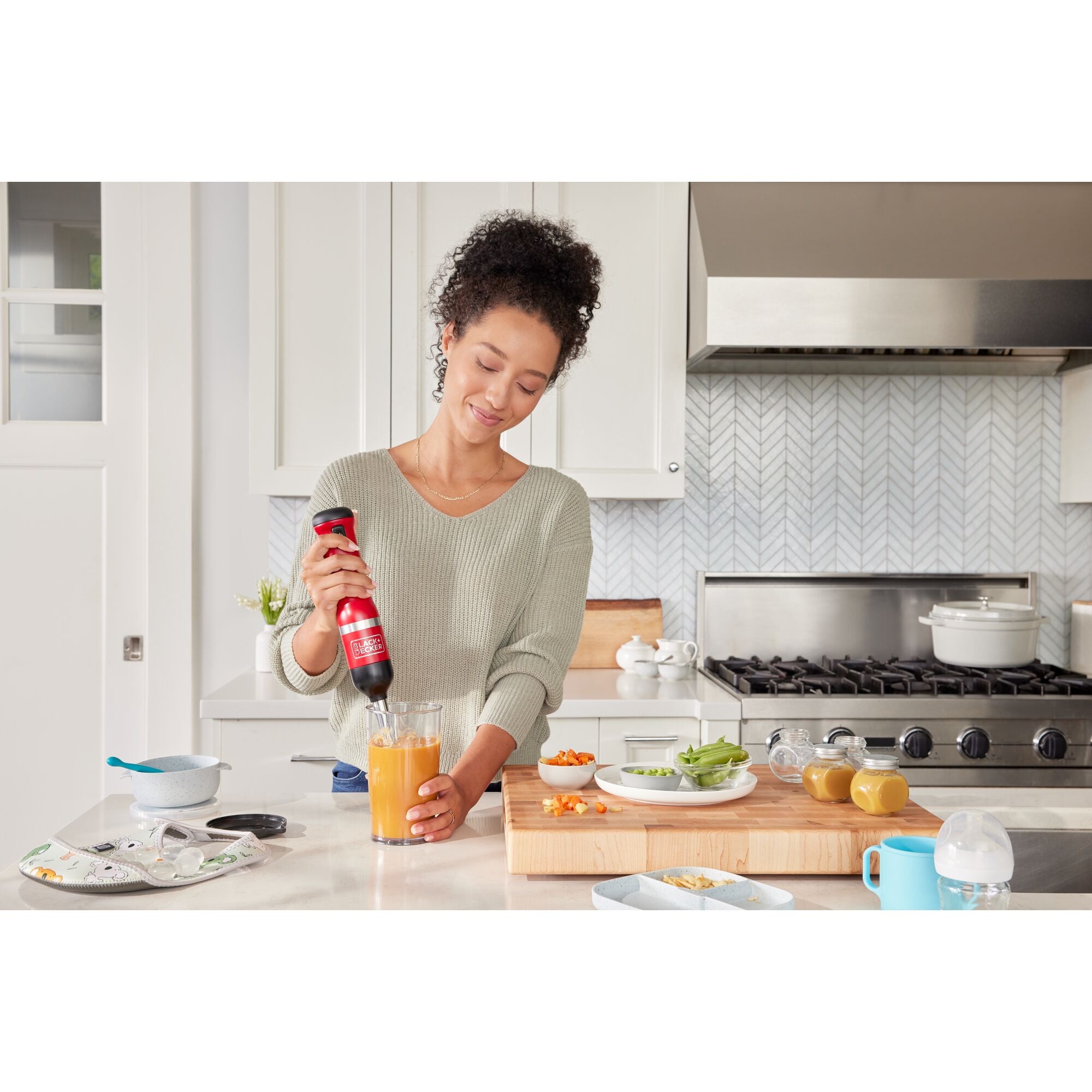 Talent lifting the lever on the red, BLACK+DECKER kitchen wand can opener to discharge the can lid in to the recycling bin