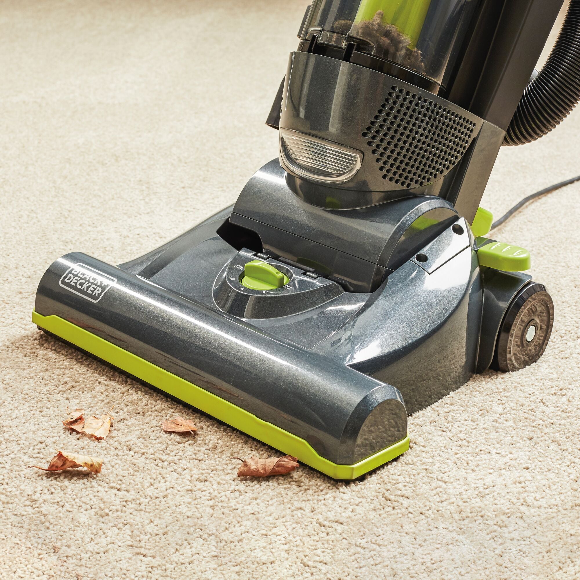 BLACK+DECKER Upright Vacuum with Anti-Allergen Hepa Filter sucking the trash from the white carpet.