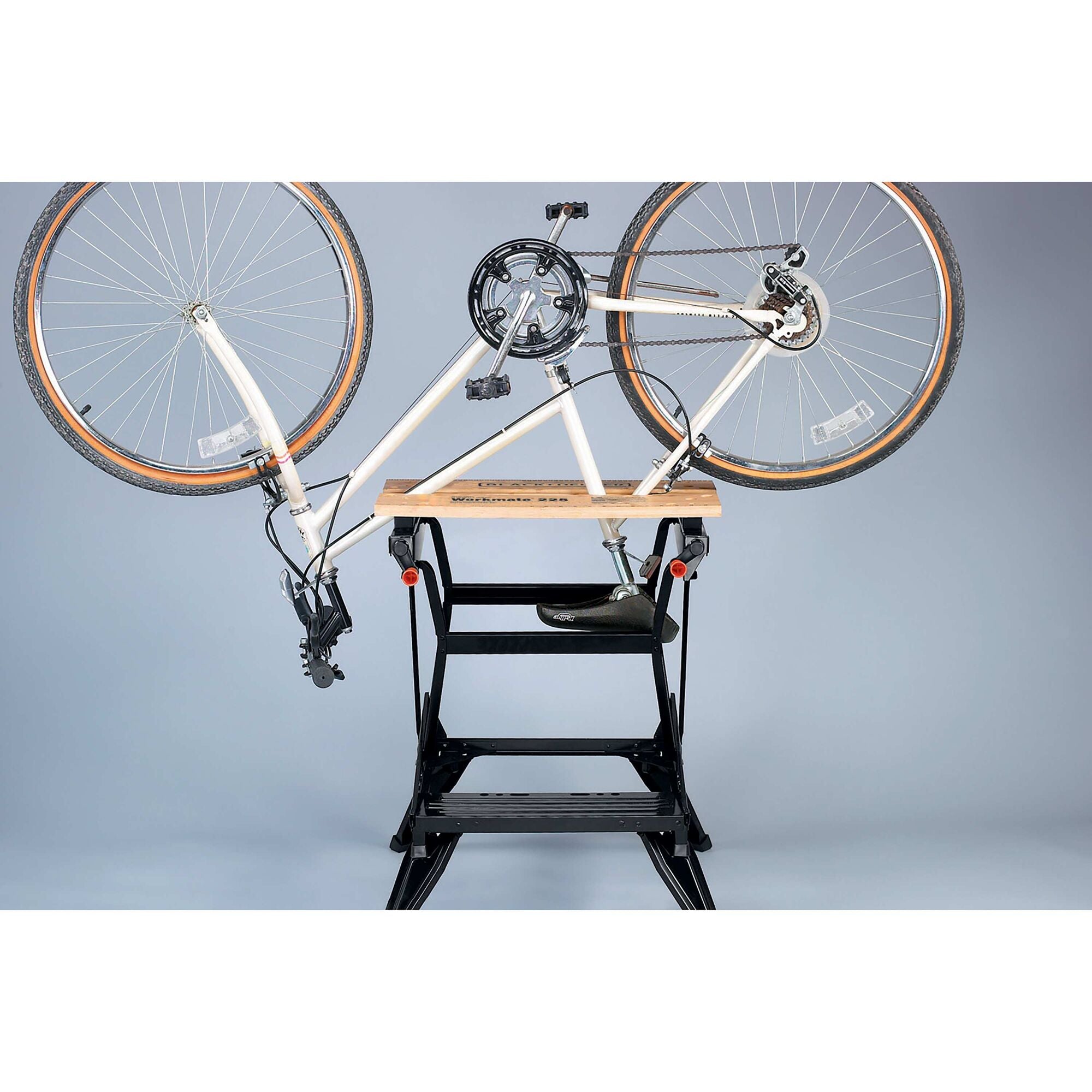 A bike clamped to the BLACK+DECKER Workmate™ 225 Portable Work Center and Vise. Adjustable jaws clamp objects of various shapes and sizes.