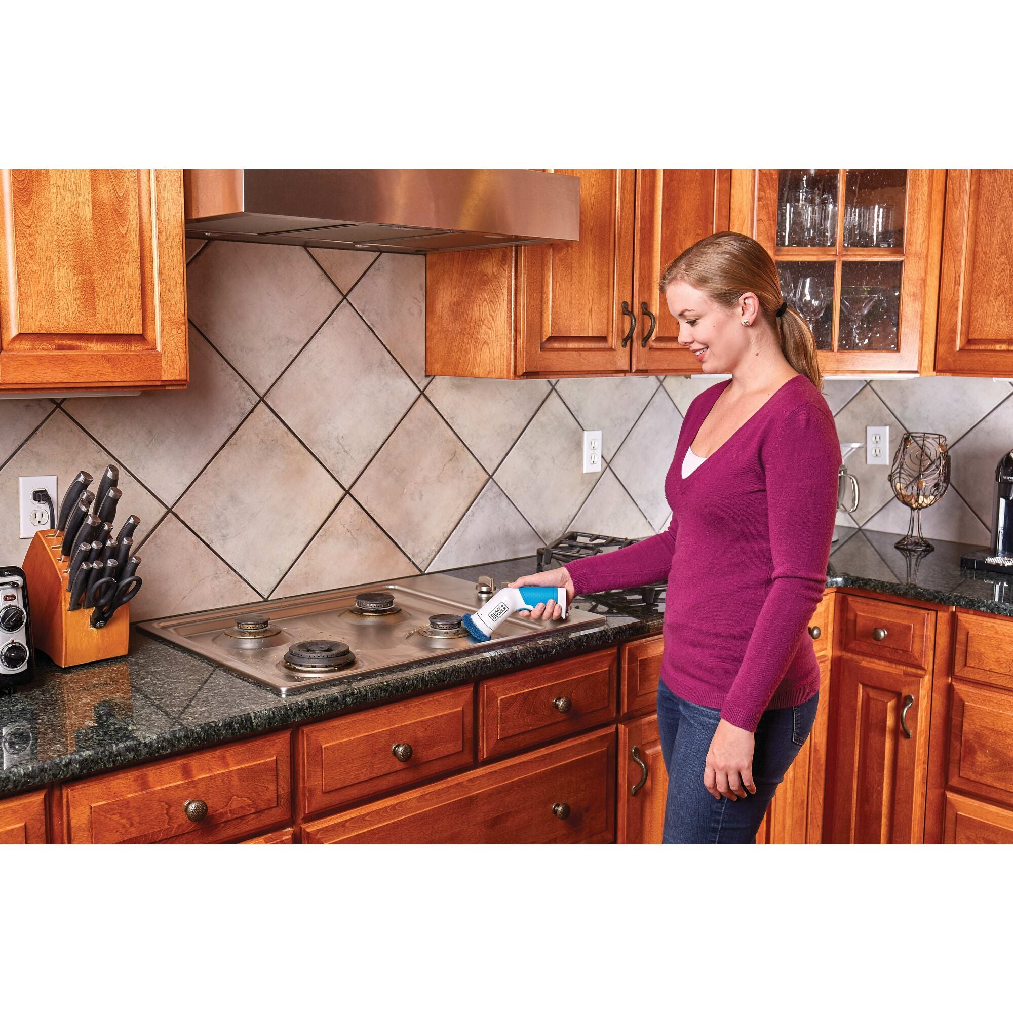 Woman using Power Scrubber Brush to clean a stovetop.