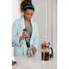 Model using the grey, BLACK+DECKER kitchen wand milk frother attachment to froth milk for a cappaccino