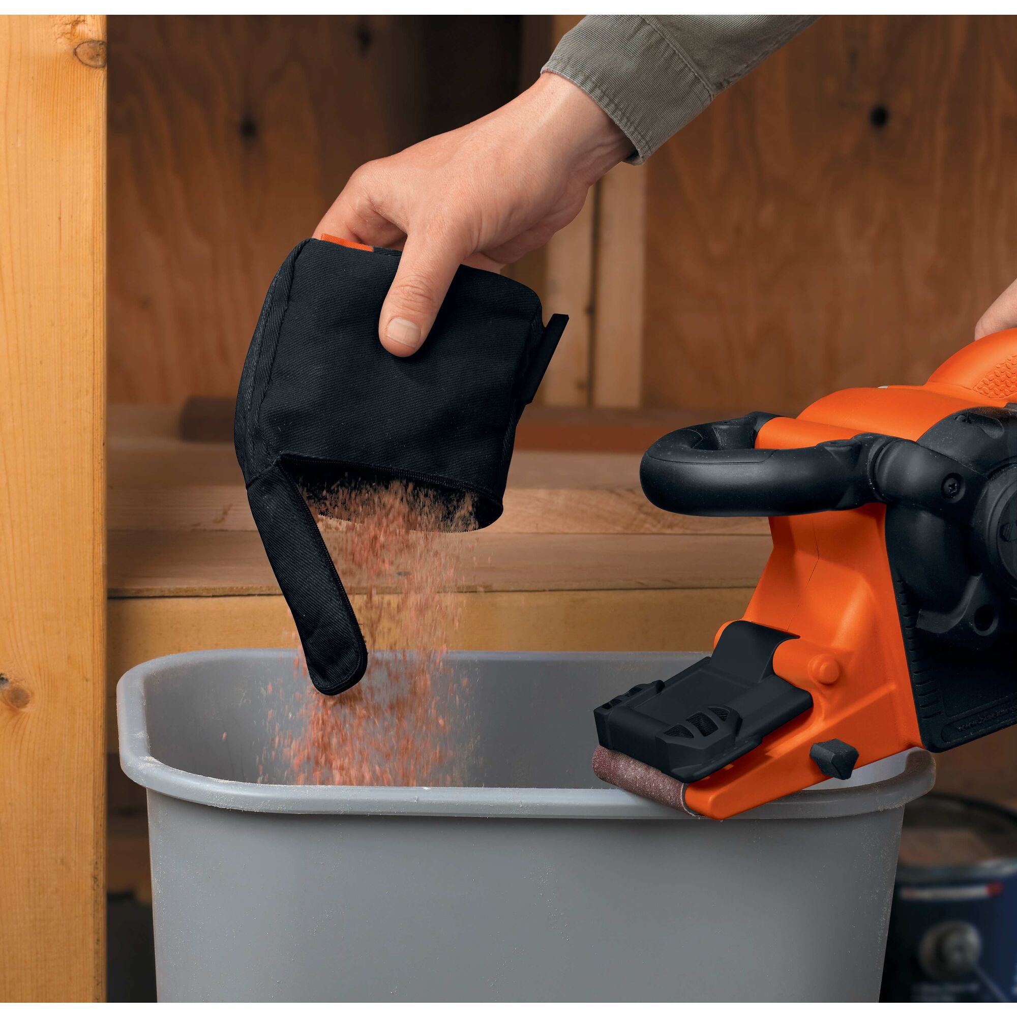 A person is emptying a dust bag of the BLACK+DECKER Belt Sander.