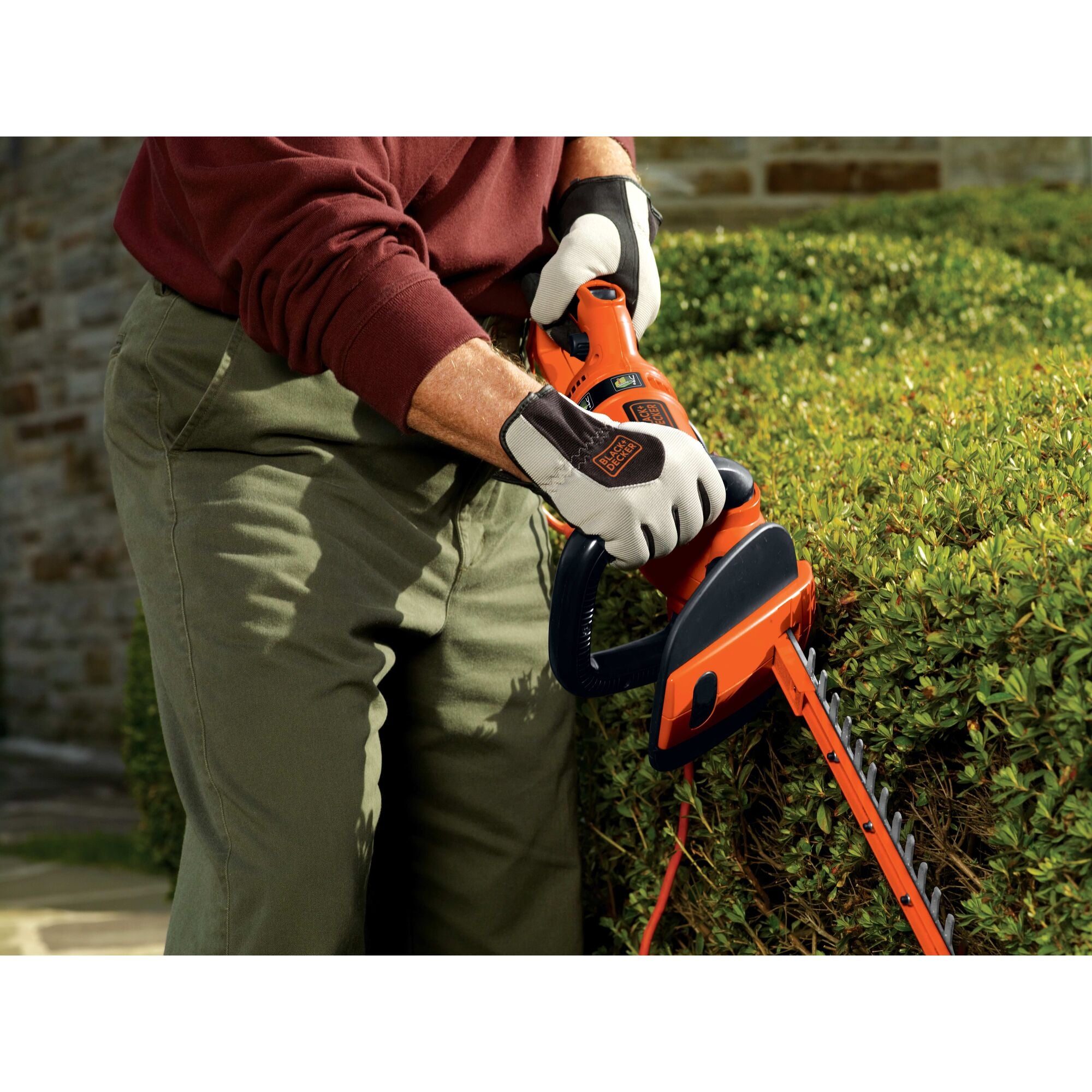 24 inch hedge trimmer with rotating handle being used by a person to trim a bush.