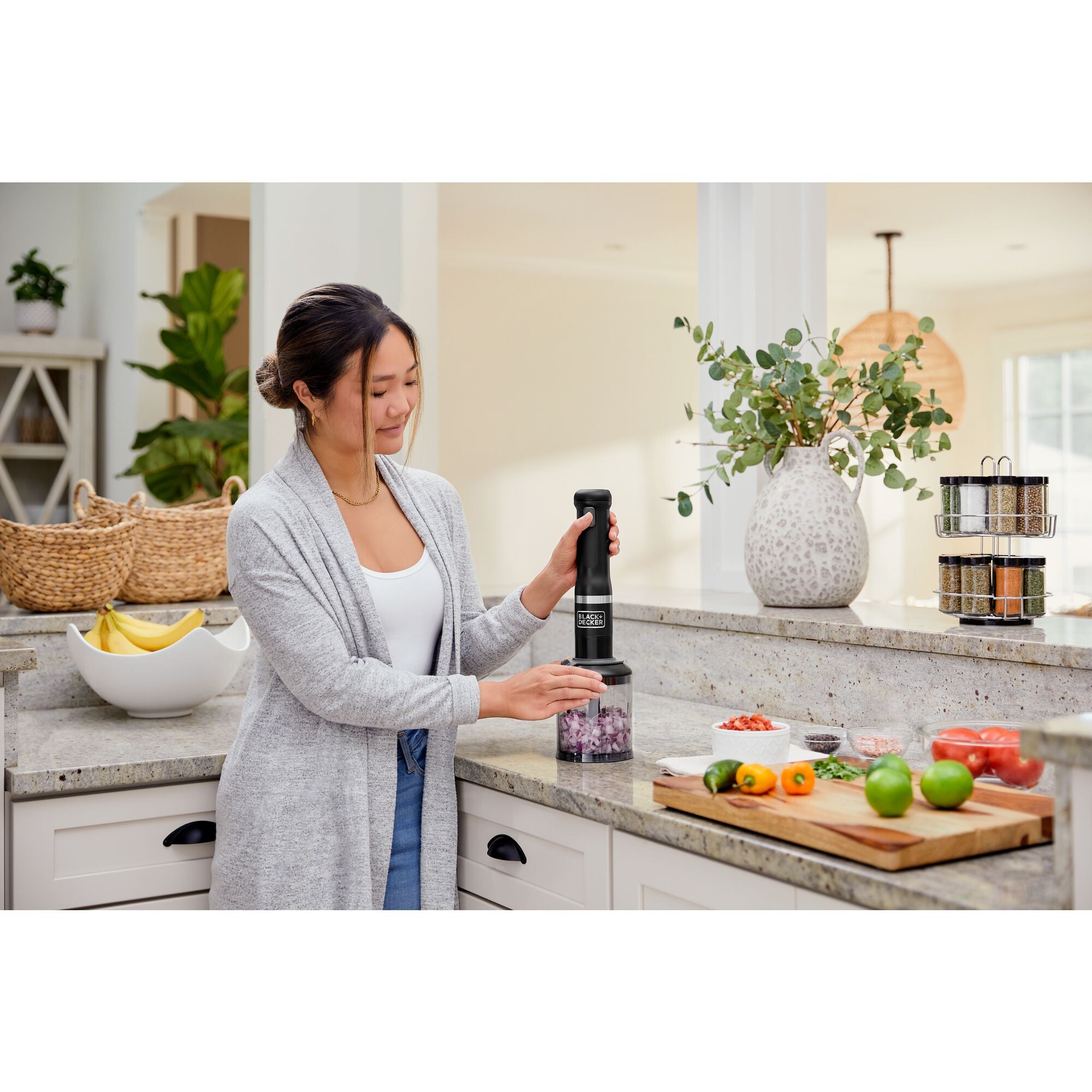 Model using the black, BLACK+DECKER kitchen wand food chopper attachment to chop onions