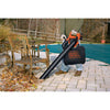 Lithium sweeper and vacuum being used to blow leaves from beneath a chair.
