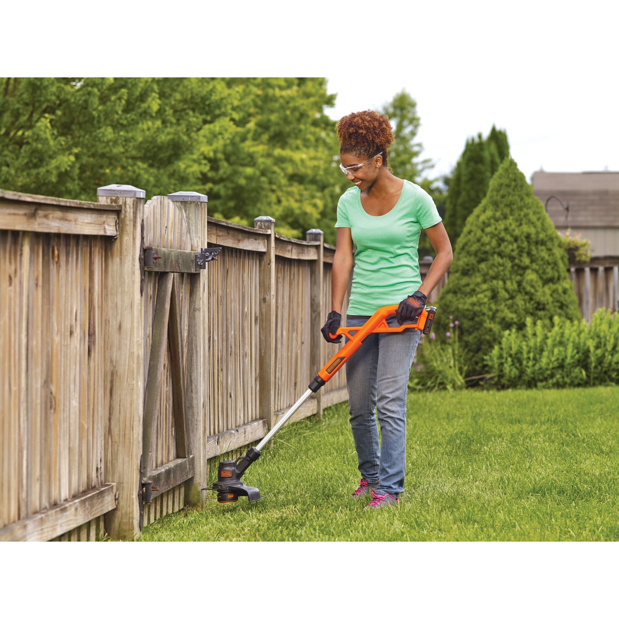 A woman is trimming grass using a BLACK+DECKER 20V MAX* String Trimmer/Edger Kit.