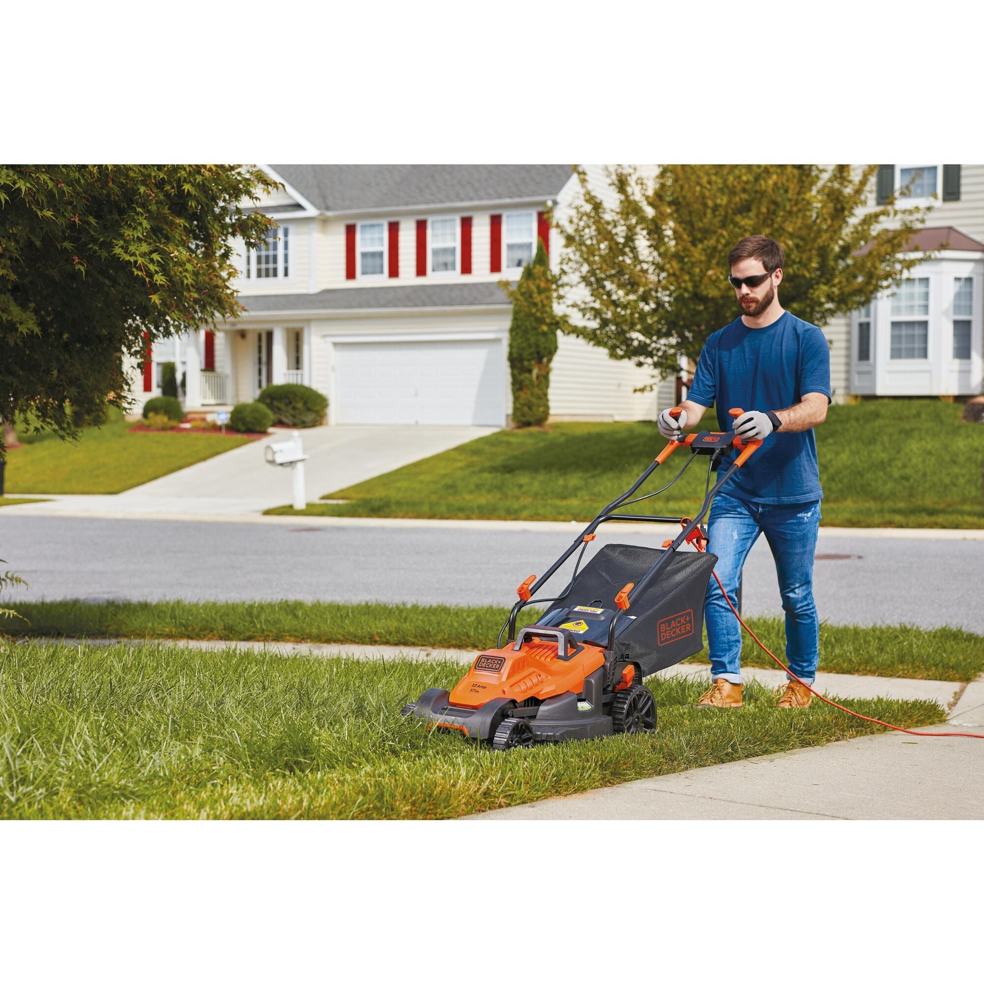 A man is mowing his garden using a BLACK+DECKER Electric Lawn Mower.