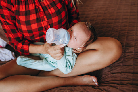 A mother is bottle-feeding her baby