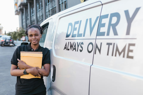 Frau mit Paket vor einem Lieferwagen in der Stadt, mit dem Text 'Delivery always on time' auf dem Fahrzeug.