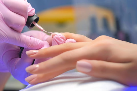 Shellac manicure being applied in a pink colour
