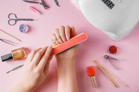 Nail file being used to file nail with various nail tools in the background