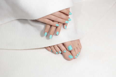 Shellac in a turquoise colour applied to a hand during a manicure and foot during a pedicure