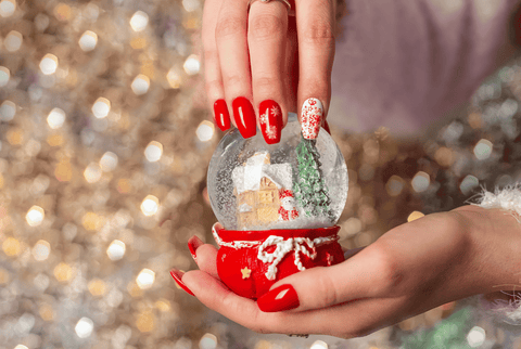 Hand with Christmas themed nails holding a snow globe