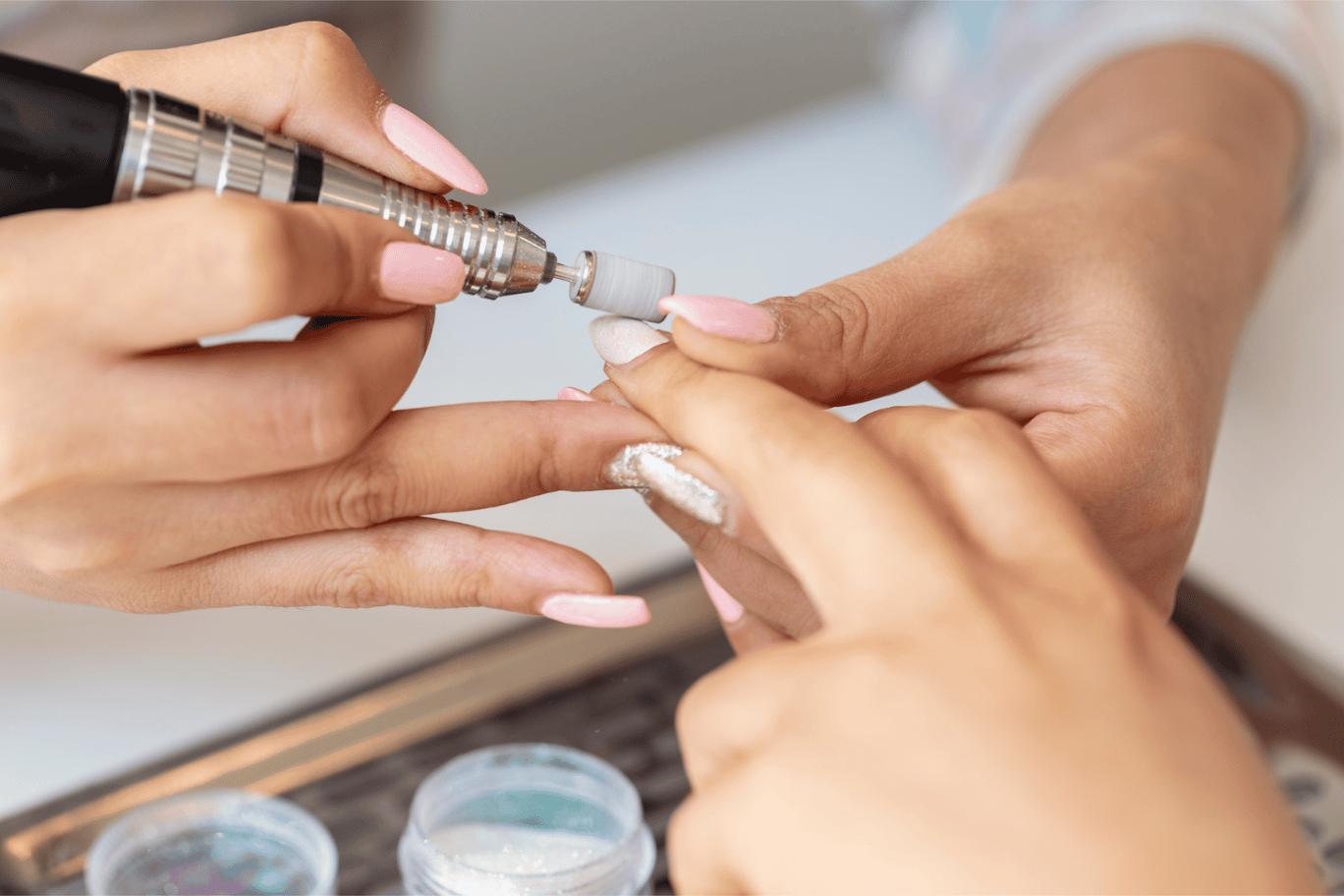 Nail drill being used to file nail during a manicure