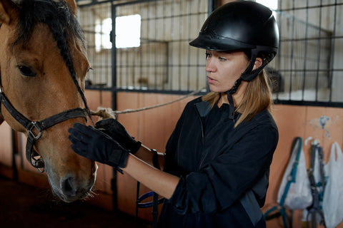 A horse rider with helmet on harnessing a horse