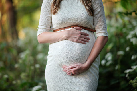 A close-up picture of a clothed woman's pregnant stomach