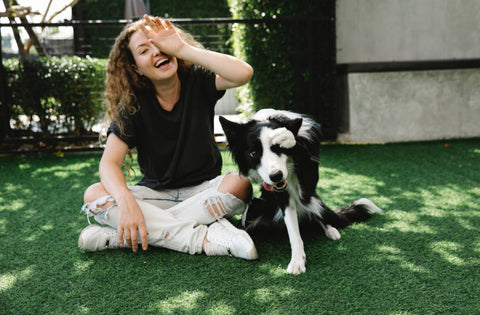 Dog and owner smiling and posing with hands over eyes in the shade