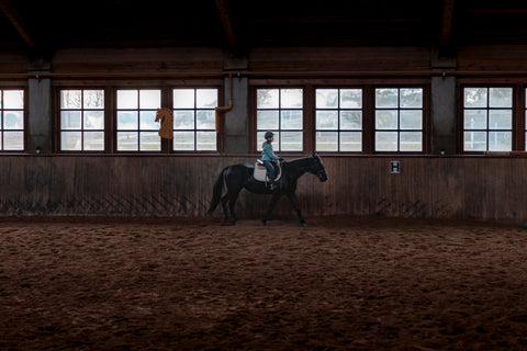 A rider inside a training facilities riding on top of their horse