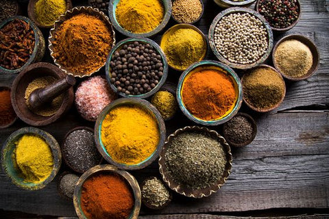 An aerial view of bowls of different powdered herbs and spices