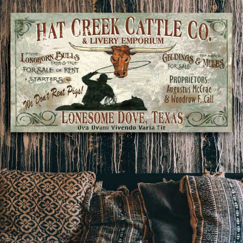 Lonesome Dove, TX sign hanging above a couch against a wood paneled wall. Latin motto and we don't rent pigs!