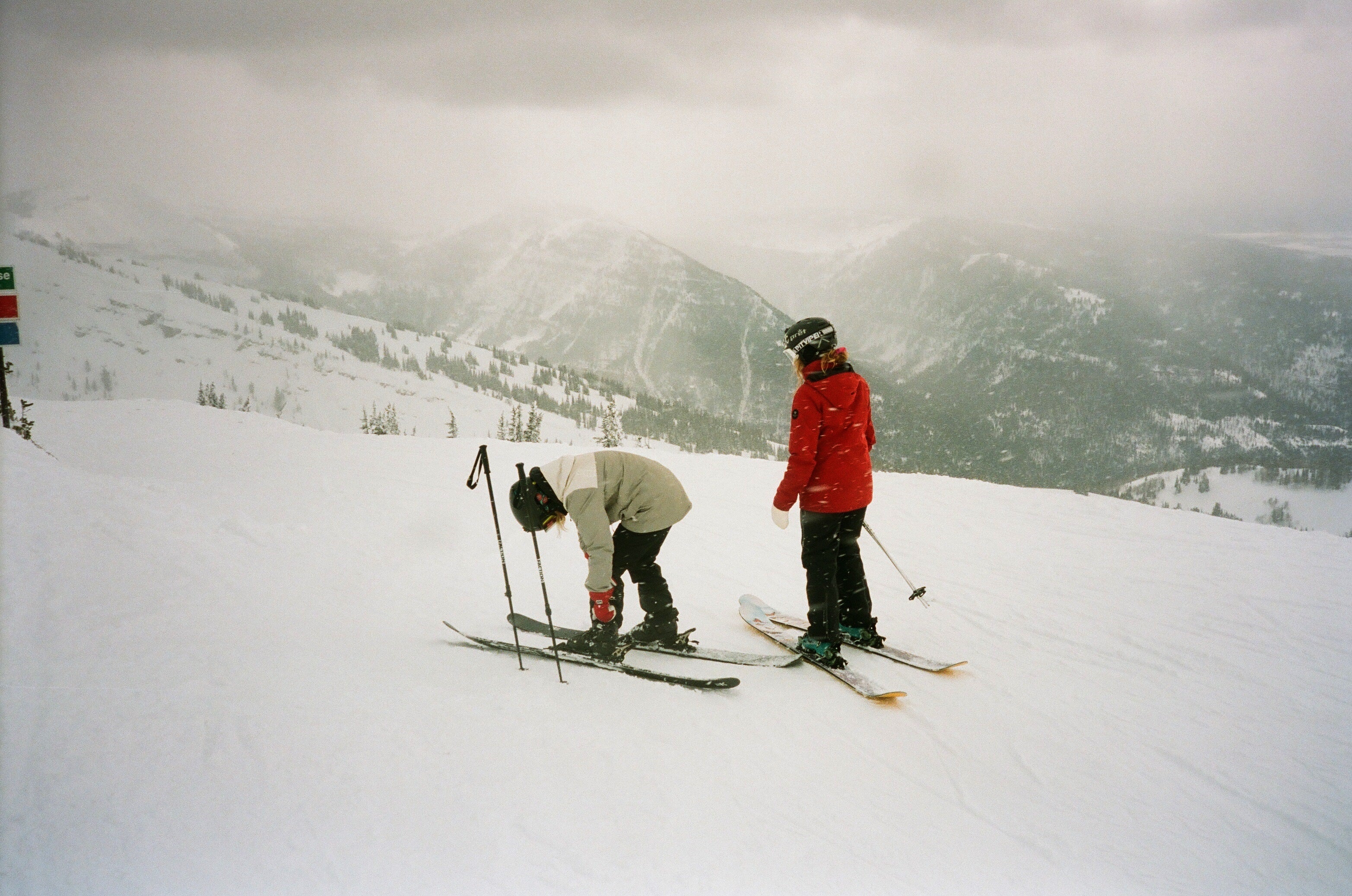 Two friends preparing to ski down a mountain