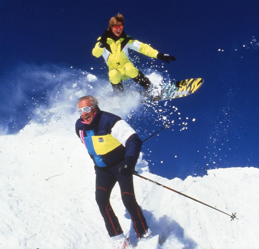 Two men skiing and snowboarding in the 1980s