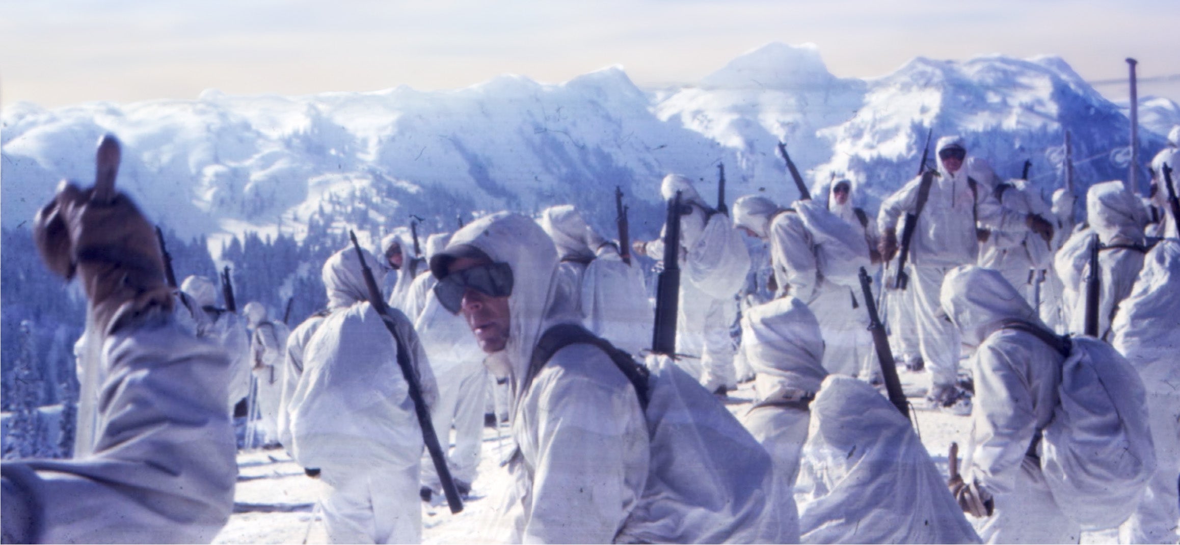 10th Mountain Division on top of a mountain ridge wearing their white uniforms