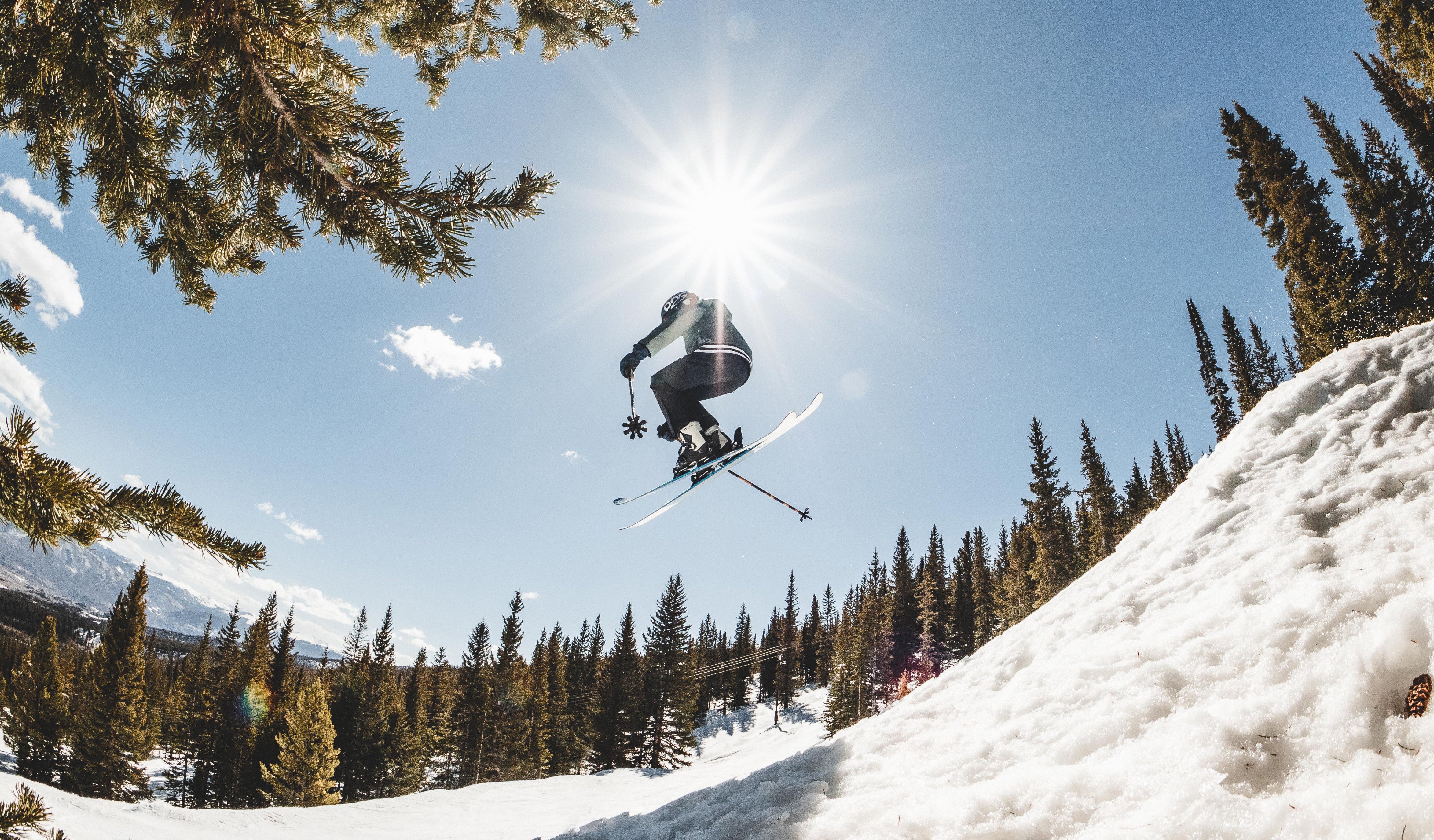 Kid jumping off of a ski jump on his skis in Obermeyer apparel