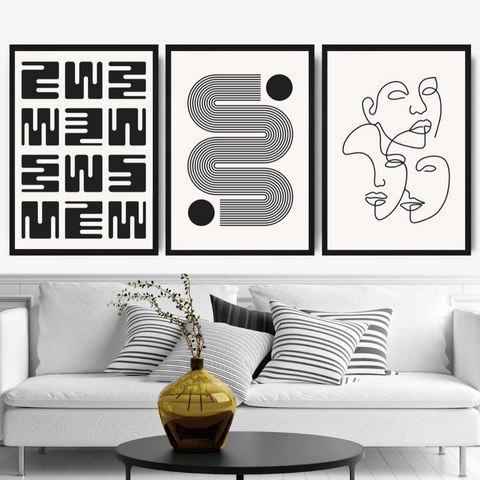 3 posters with black and white modern and abstract arts in a living room with a grey sofa.