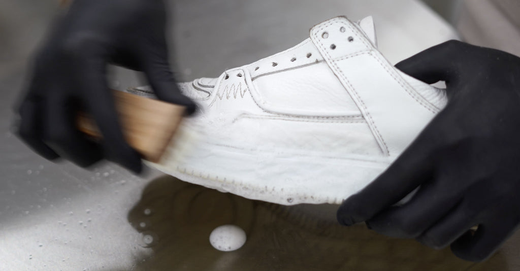 Abbildung eines weißen Sneaker der mit einer Bürste gereinigt wird