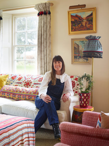 Chloe Jonason, vintage textile worker sat on her sofa surrounded by brightly coloured fabrics.