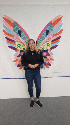 Lady standing in front of a quilt of wings